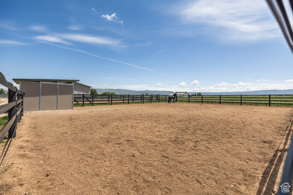 View of yard with an enclosed riding area, a mountain view, an outbuilding, and a view of countryside