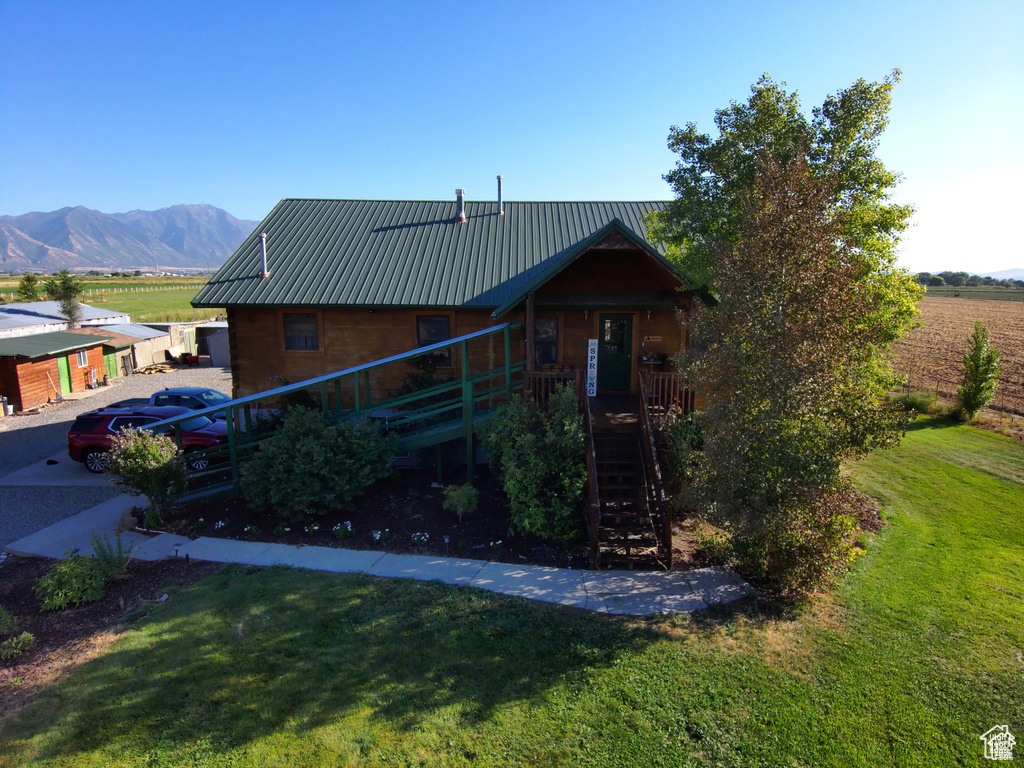 View of front of home featuring stairway, a front lawn, metal roof, and a mountain view