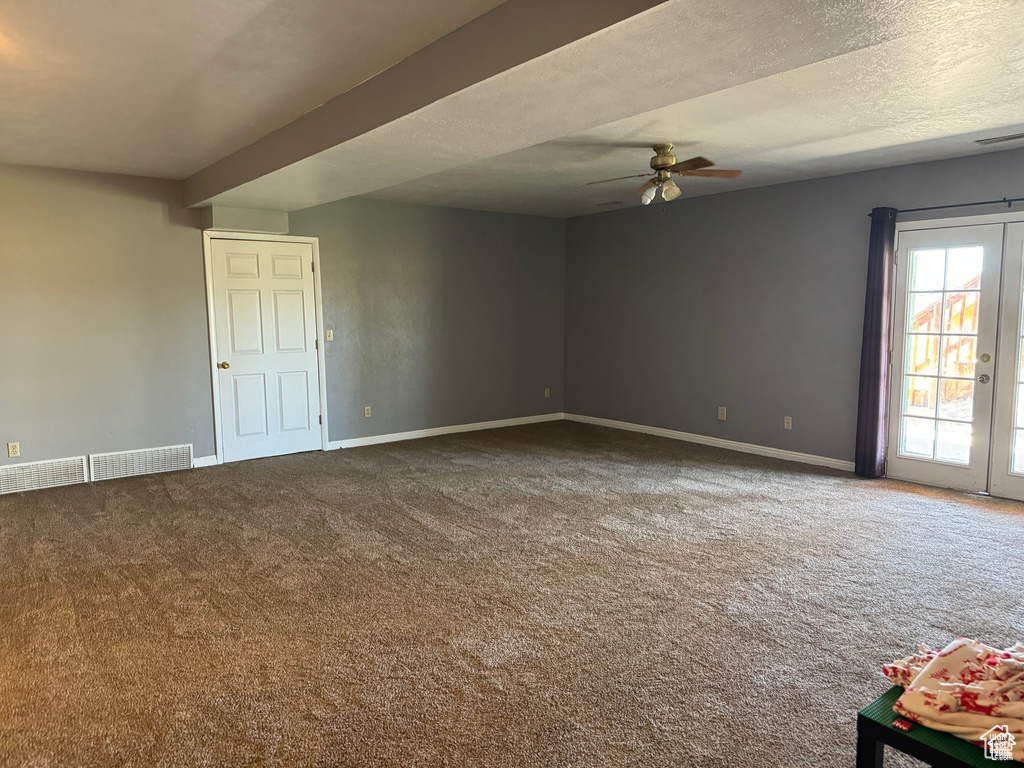 Carpeted empty room featuring a ceiling fan and baseboards