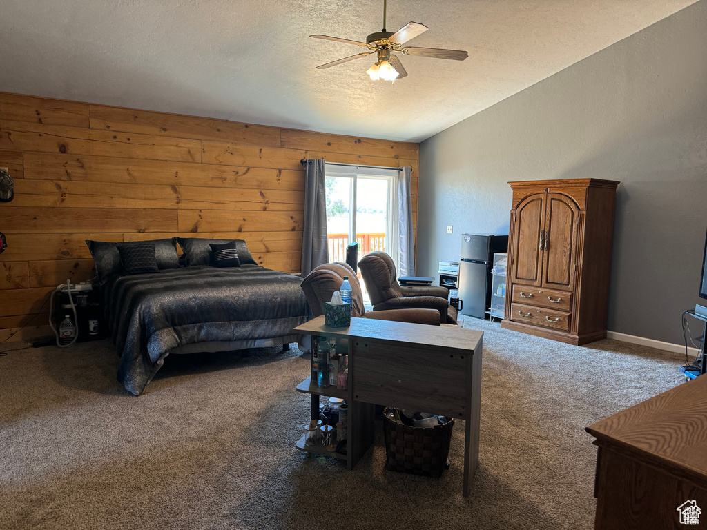 Bedroom featuring carpet, lofted ceiling, a textured ceiling, ceiling fan, and wooden walls