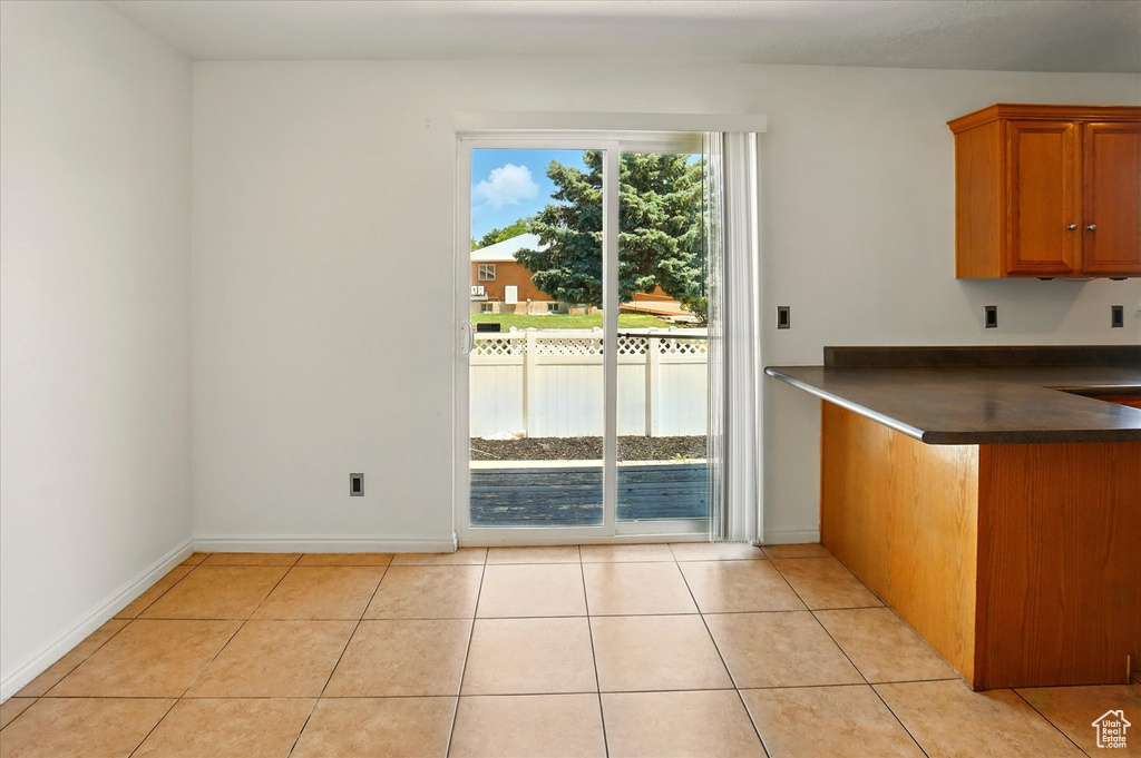 Kitchen with dark countertops, brown cabinetry, light tile patterned flooring, and baseboards