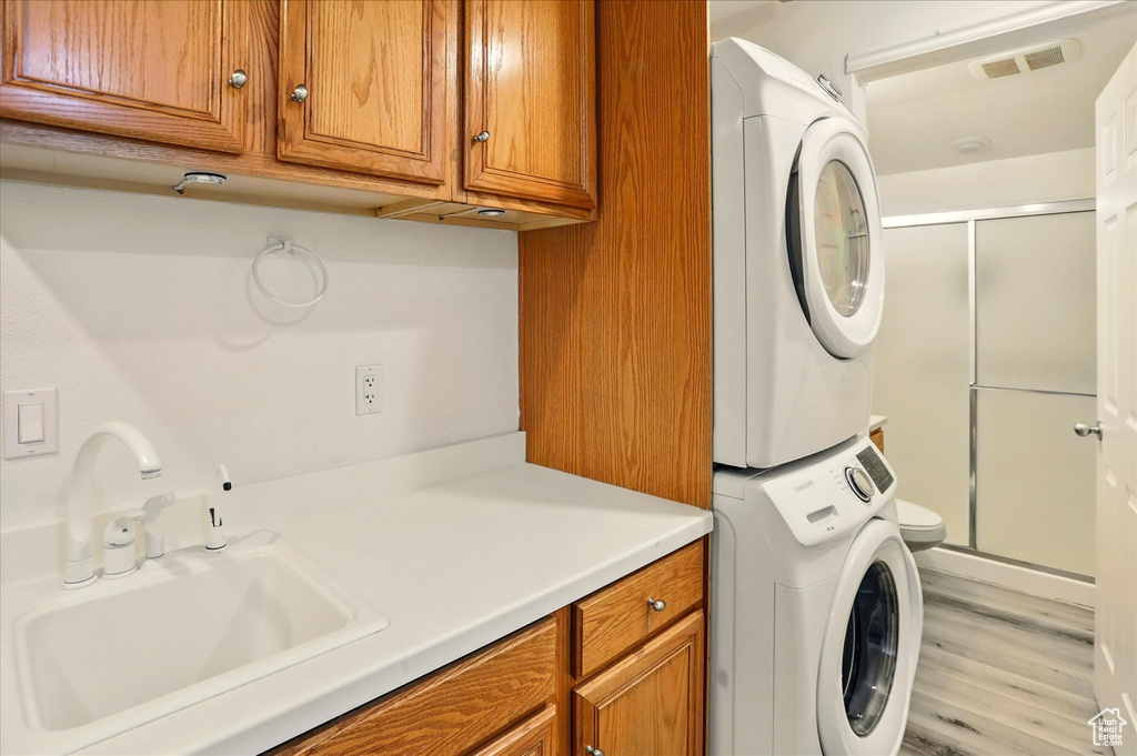 Laundry area featuring stacked washer / dryer and wood finished floors