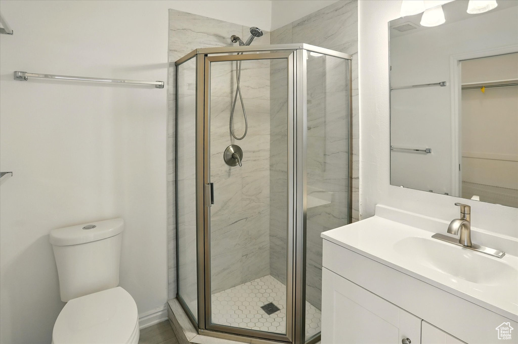 Bathroom with vanity, a shower stall, toilet, and a spacious closet