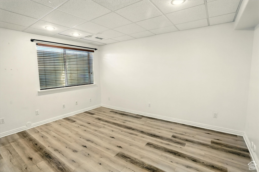 Spare room with wood finished floors, baseboards, a paneled ceiling, and recessed lighting