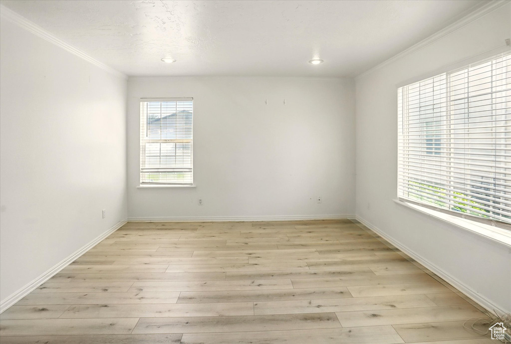 Unfurnished room with crown molding, light wood-style flooring, baseboards, and recessed lighting