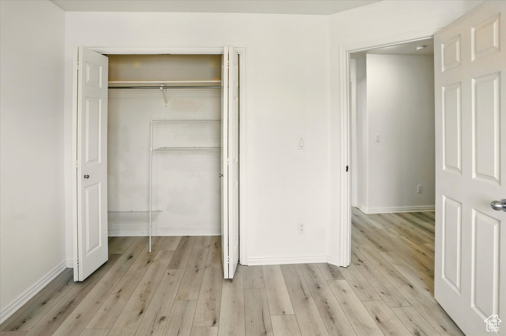 Unfurnished bedroom featuring a closet, light wood-type flooring, and baseboards