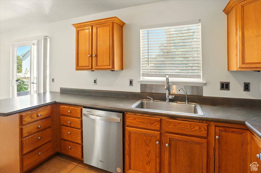 Kitchen featuring dishwasher, a sink, brown cabinetry, and a peninsula