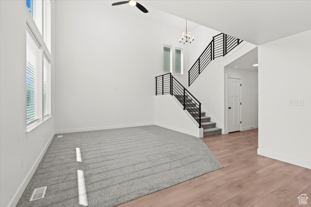 Entryway featuring stairway, baseboards, a ceiling fan, wood finished floors, and a high ceiling