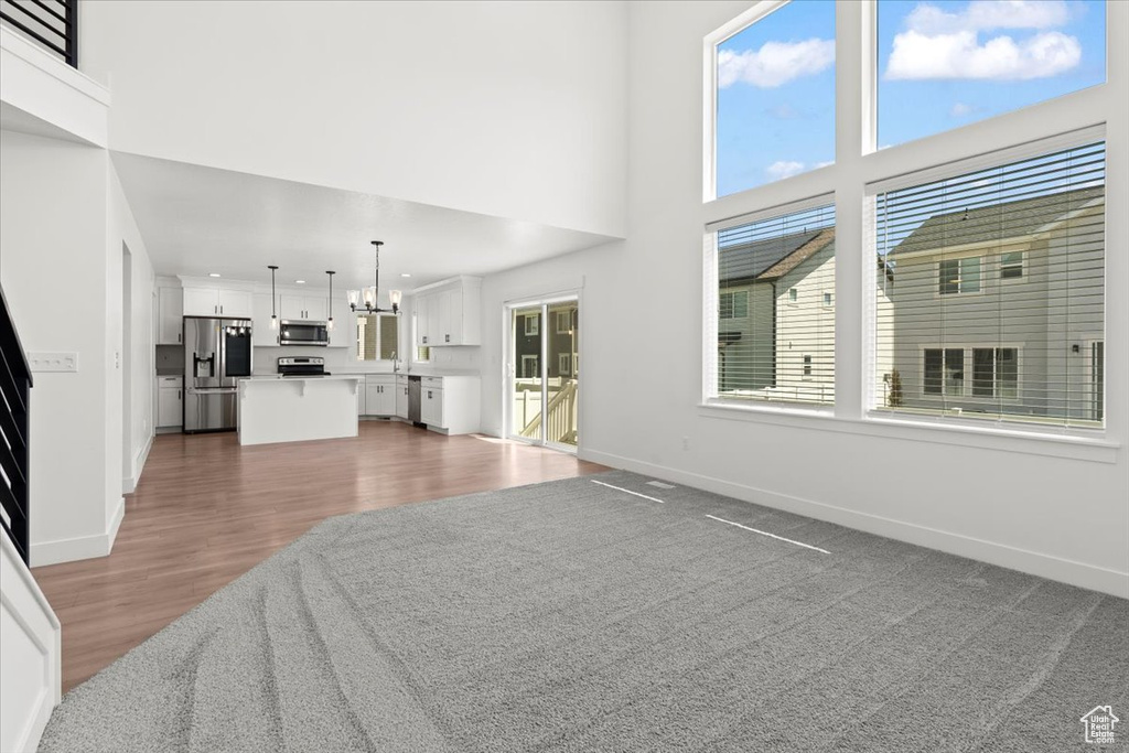 Unfurnished living room featuring a chandelier, baseboards, dark wood finished floors, and a sink