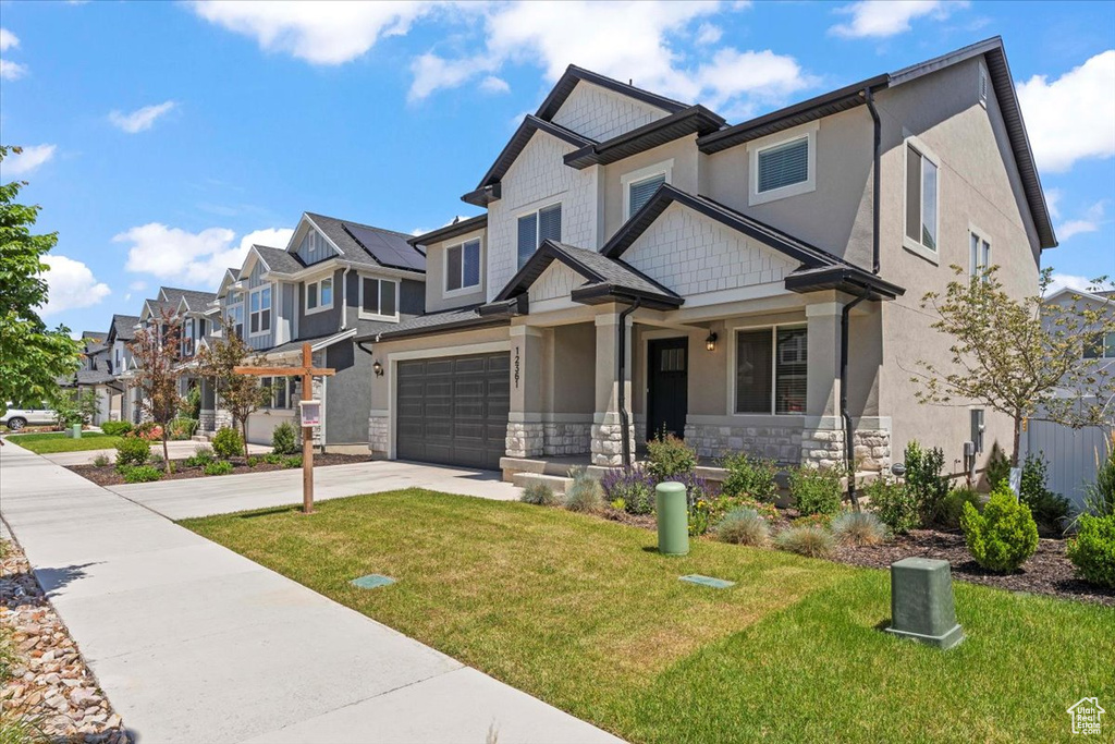 Craftsman-style house featuring stone siding, a residential view, concrete driveway, and a front lawn