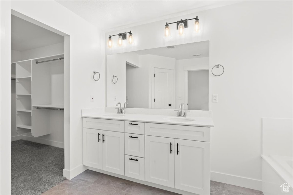 Full bath featuring double vanity, baseboards, and a bathtub