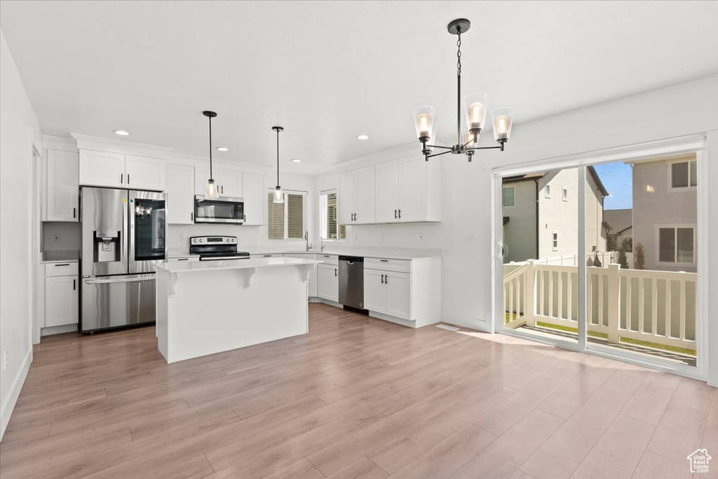 Kitchen with appliances with stainless steel finishes, recessed lighting, white cabinets, light wood-style flooring, and a kitchen island