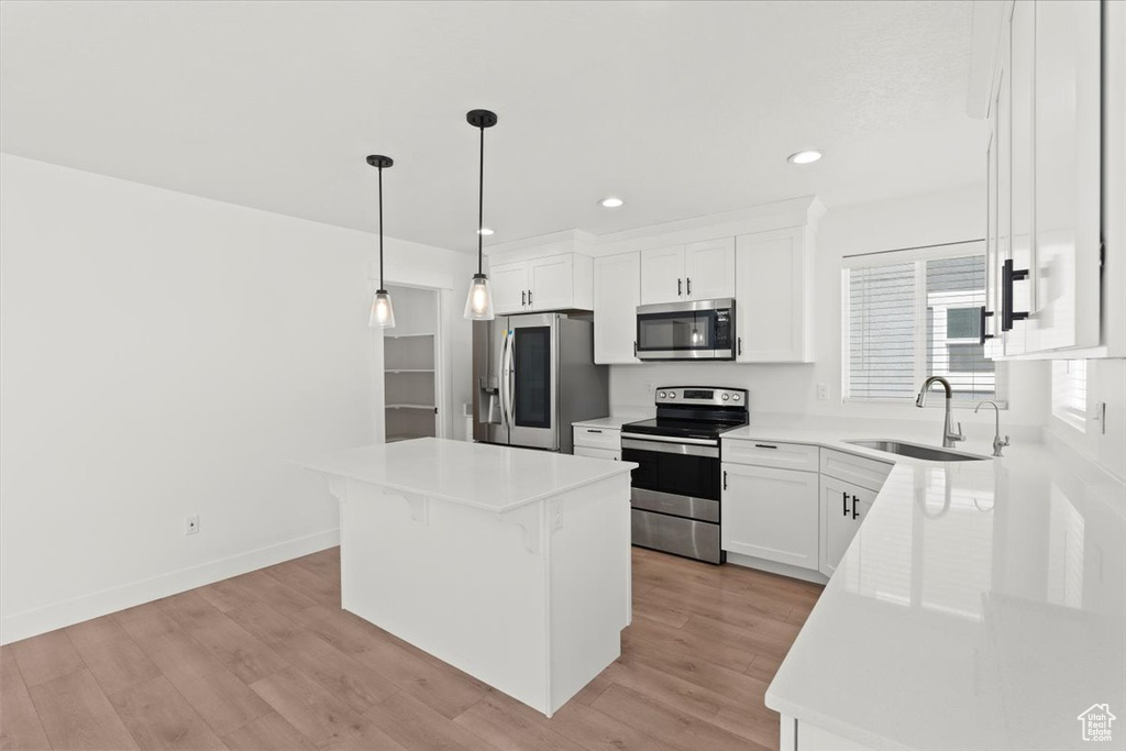 Kitchen featuring stainless steel appliances, a sink, a kitchen island, white cabinets, and recessed lighting