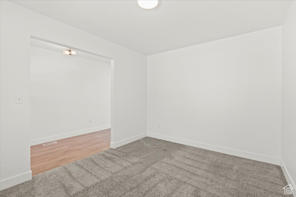 Empty room with baseboards, carpet floors, and wood finished floors