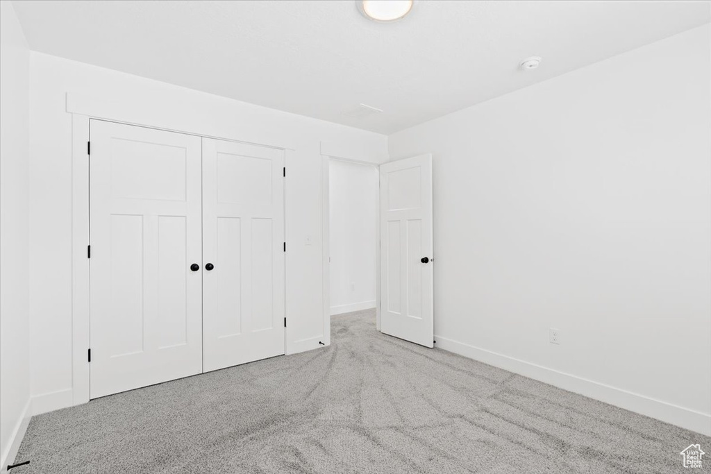 Unfurnished bedroom featuring carpet floors, baseboards, and a closet