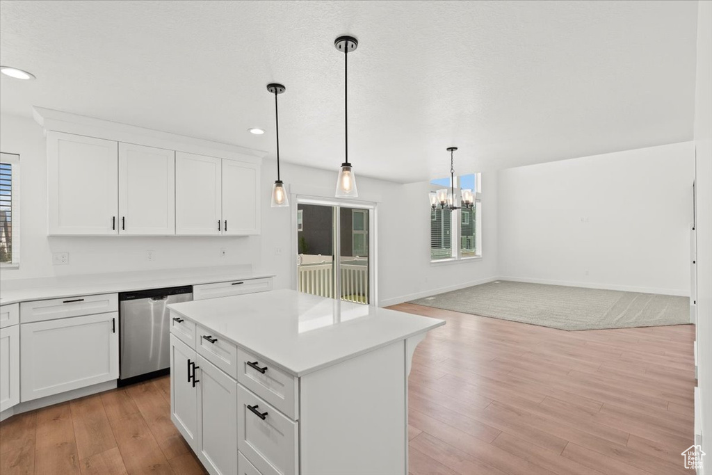 Kitchen with stainless steel dishwasher, a chandelier, open floor plan, light wood-style floors, and light countertops