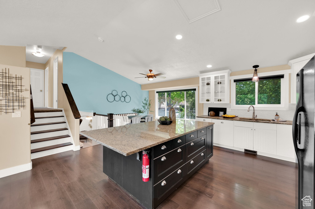 Kitchen with a sink, white cabinetry, freestanding refrigerator, dark cabinetry, and vaulted ceiling