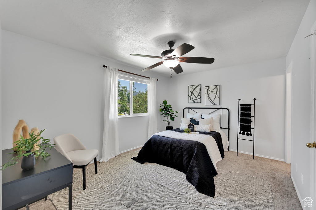 Bedroom featuring baseboards, light carpet, and ceiling fan