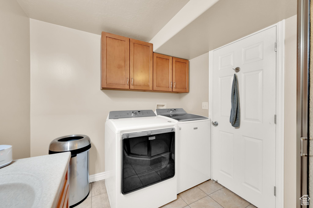Laundry room featuring cabinet space, washing machine and dryer, and light tile patterned floors