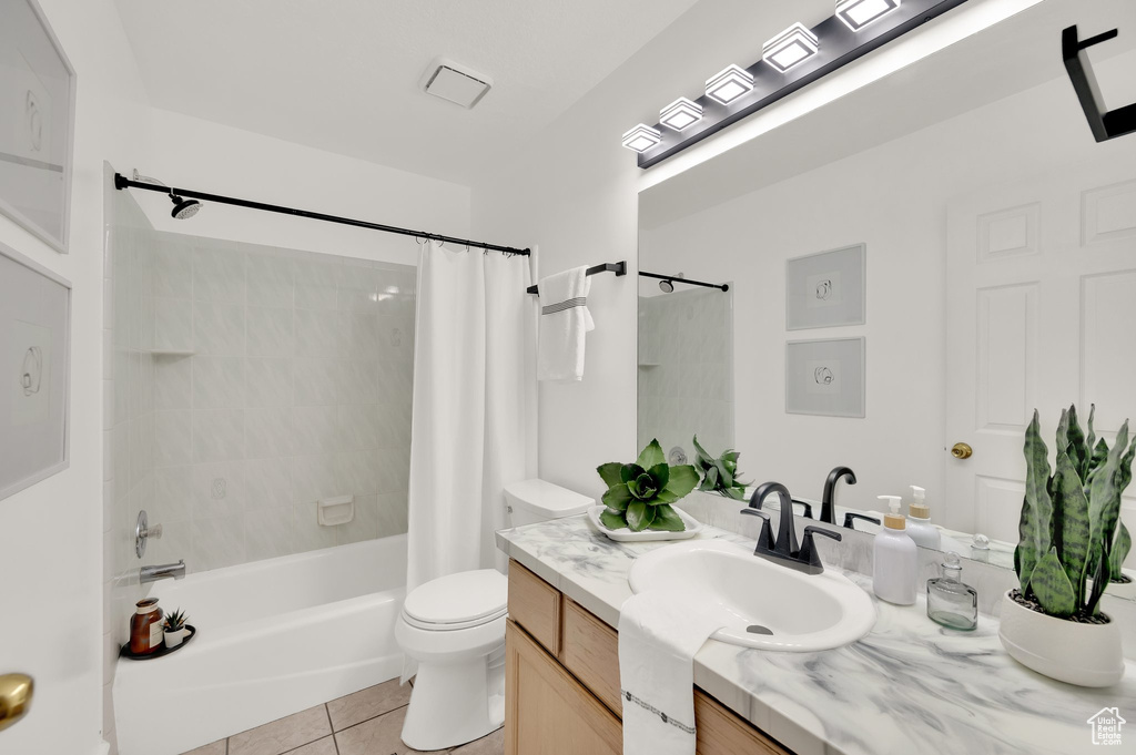 Bathroom with vanity, tile patterned floors, toilet, and shower / bathtub combination with curtain
