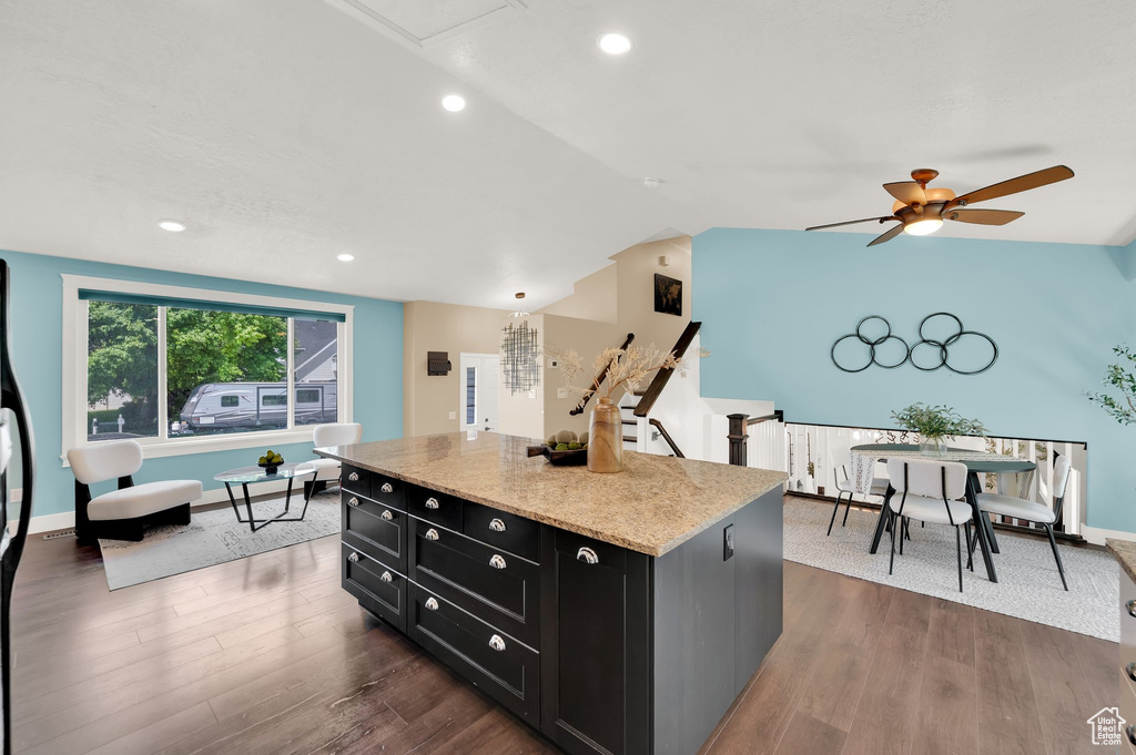 Kitchen with dark cabinets, vaulted ceiling, ceiling fan, a center island, and dark wood finished floors