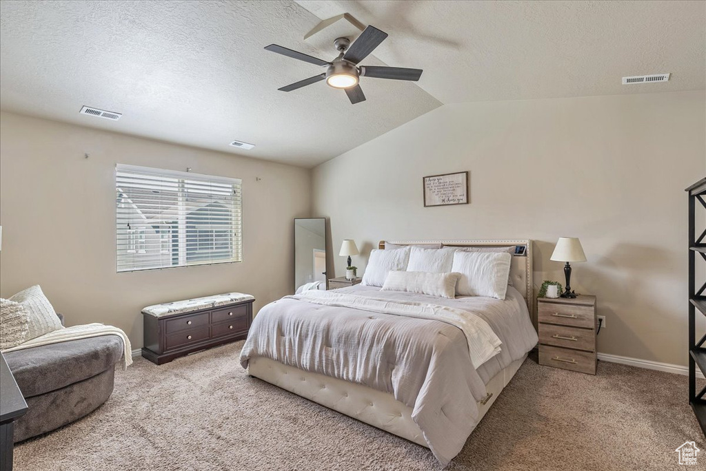 Carpeted bedroom featuring a textured ceiling, vaulted ceiling, baseboards, and ceiling fan