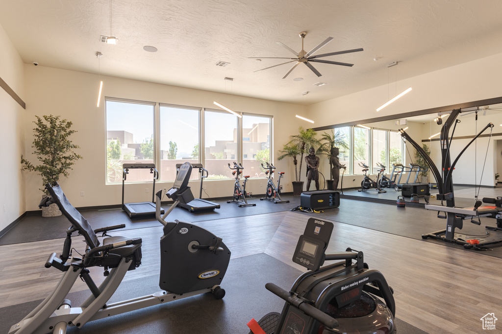 Gym with ceiling fan, baseboards, and a textured ceiling