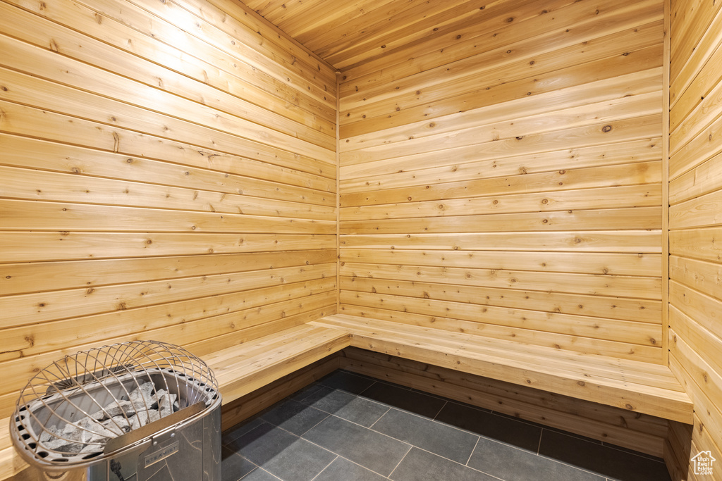 Relaxing sauna featuring tile patterned floors, wood walls, and wood ceiling