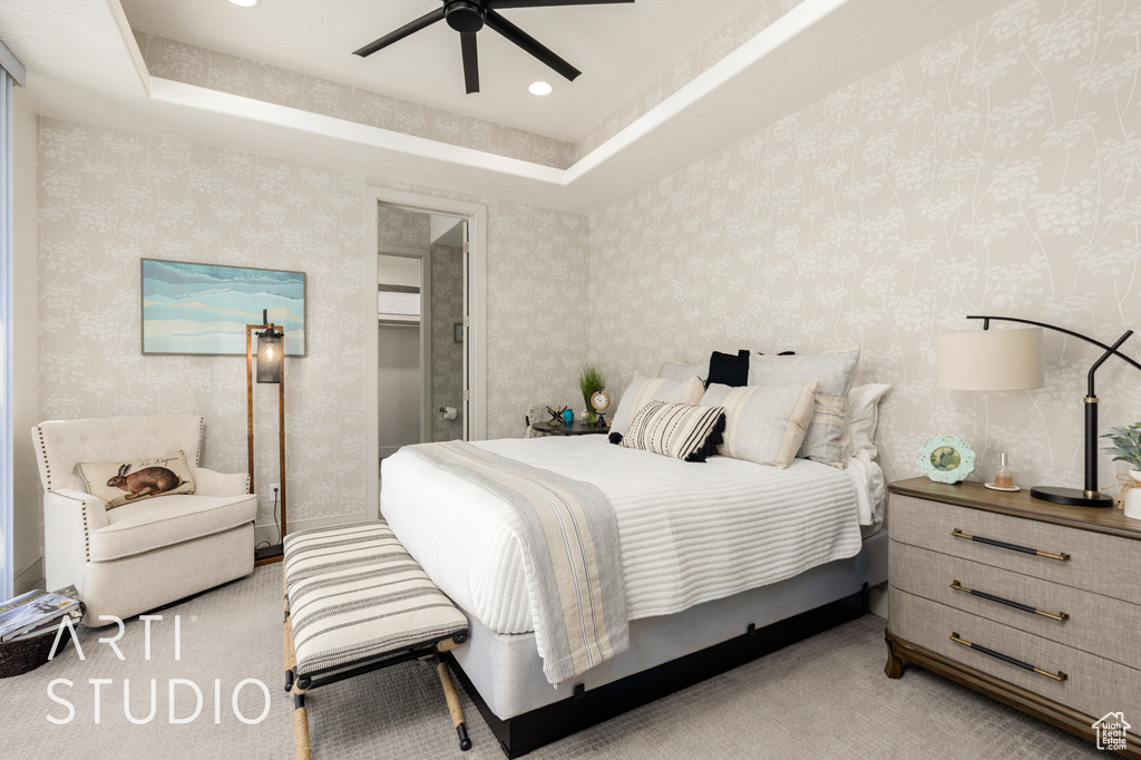 Bedroom with wallpapered walls, light colored carpet, a ceiling fan, and a raised ceiling