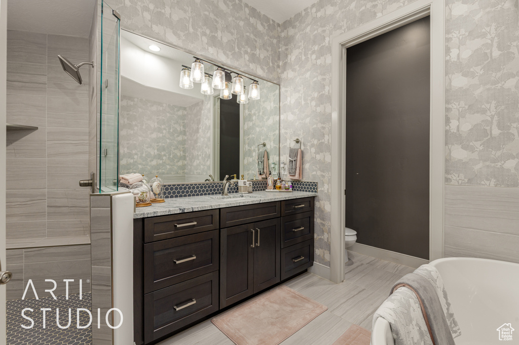 Bathroom featuring wallpapered walls, a soaking tub, vanity, a tile shower, and toilet
