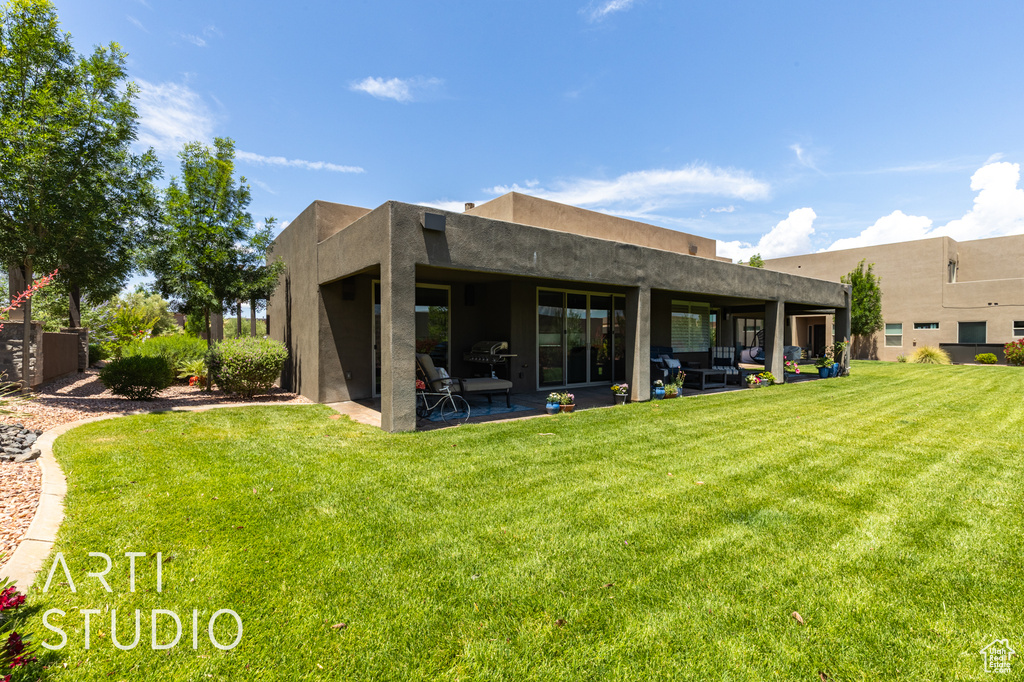Back of house with a patio area, a lawn, and stucco siding