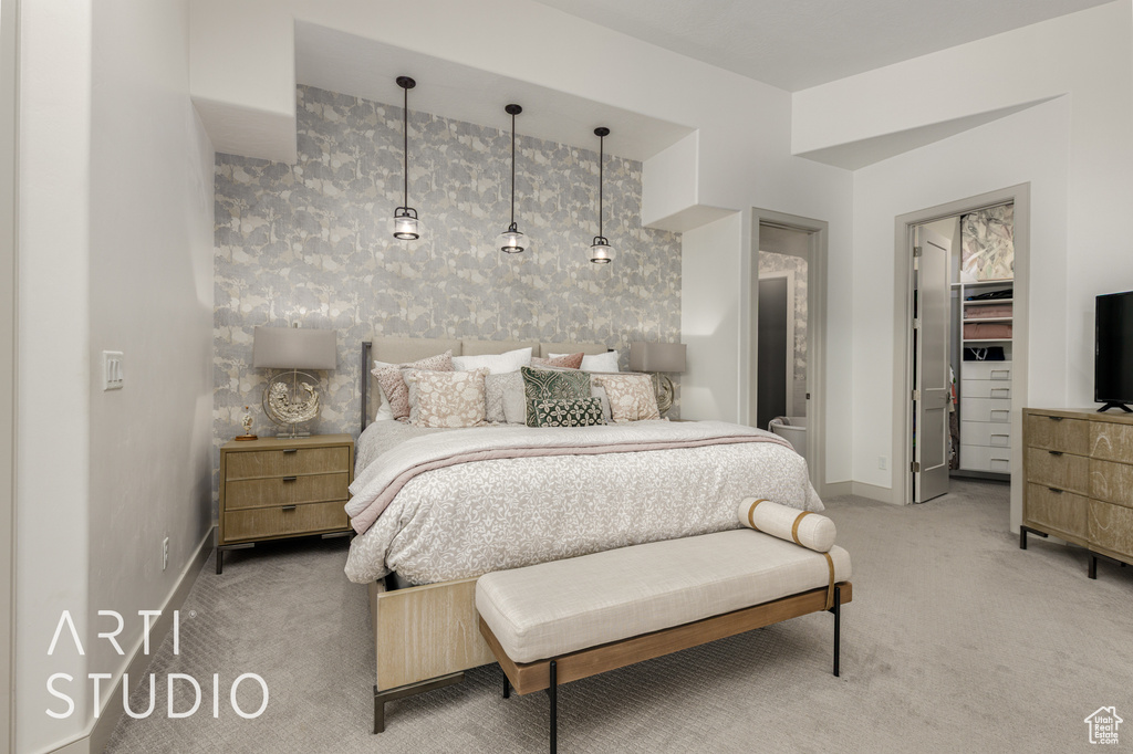 Bedroom with light colored carpet, baseboards, a walk in closet, and wallpapered walls