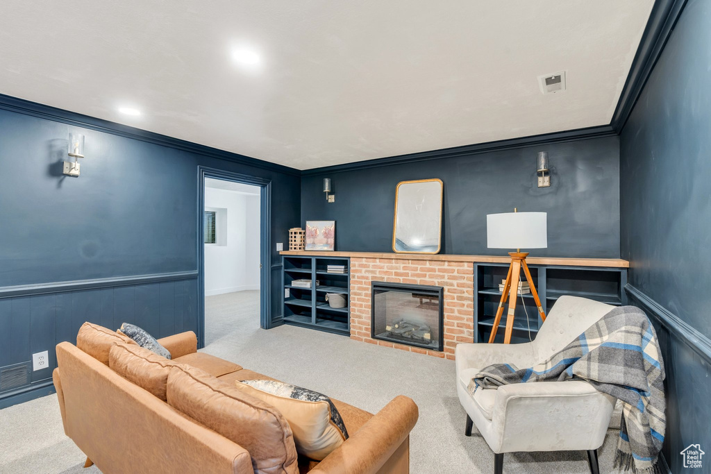 Living room featuring carpet flooring, crown molding, a fireplace, and wainscoting