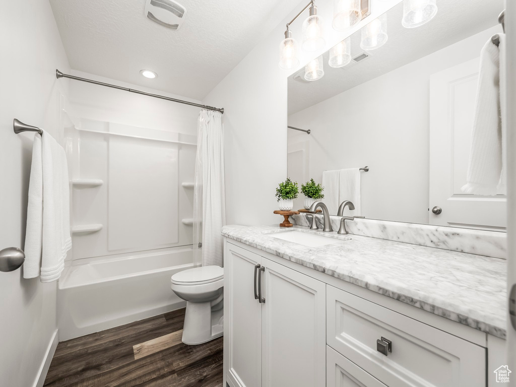 Full bath featuring wood finished floors, vanity, toilet, shower / tub combo with curtain, and recessed lighting