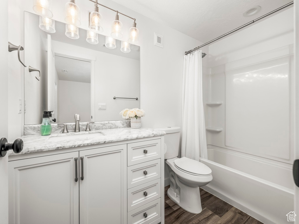 Full bathroom featuring vanity, toilet, shower / bath combination with curtain, and wood finished floors