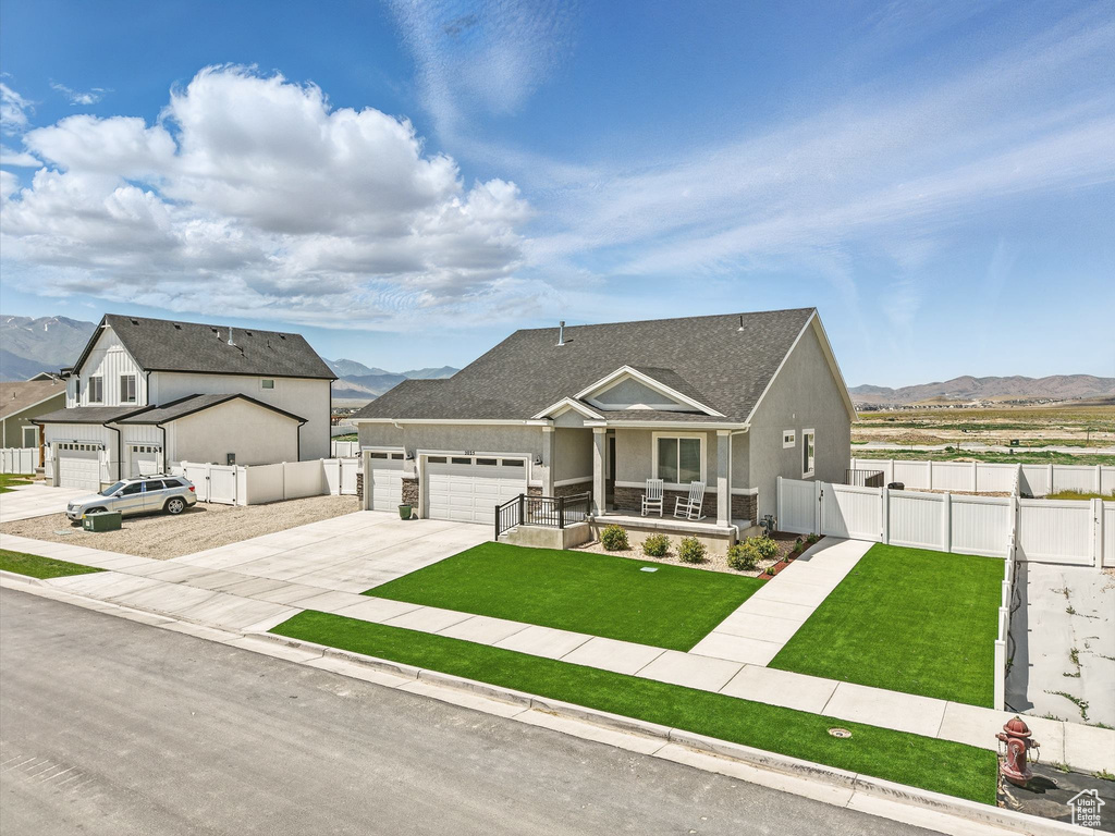 View of front of home featuring a mountain view, covered porch, an attached garage, and a gate