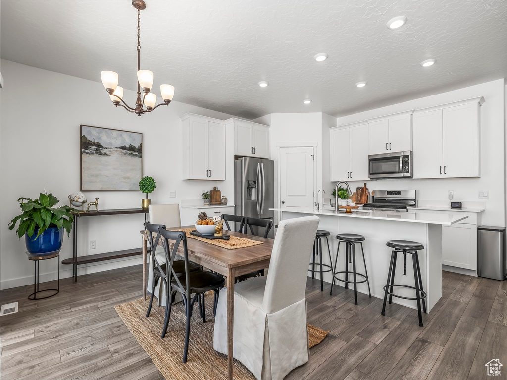 Dining area featuring wood finished floors, recessed lighting, a chandelier, and a textured ceiling