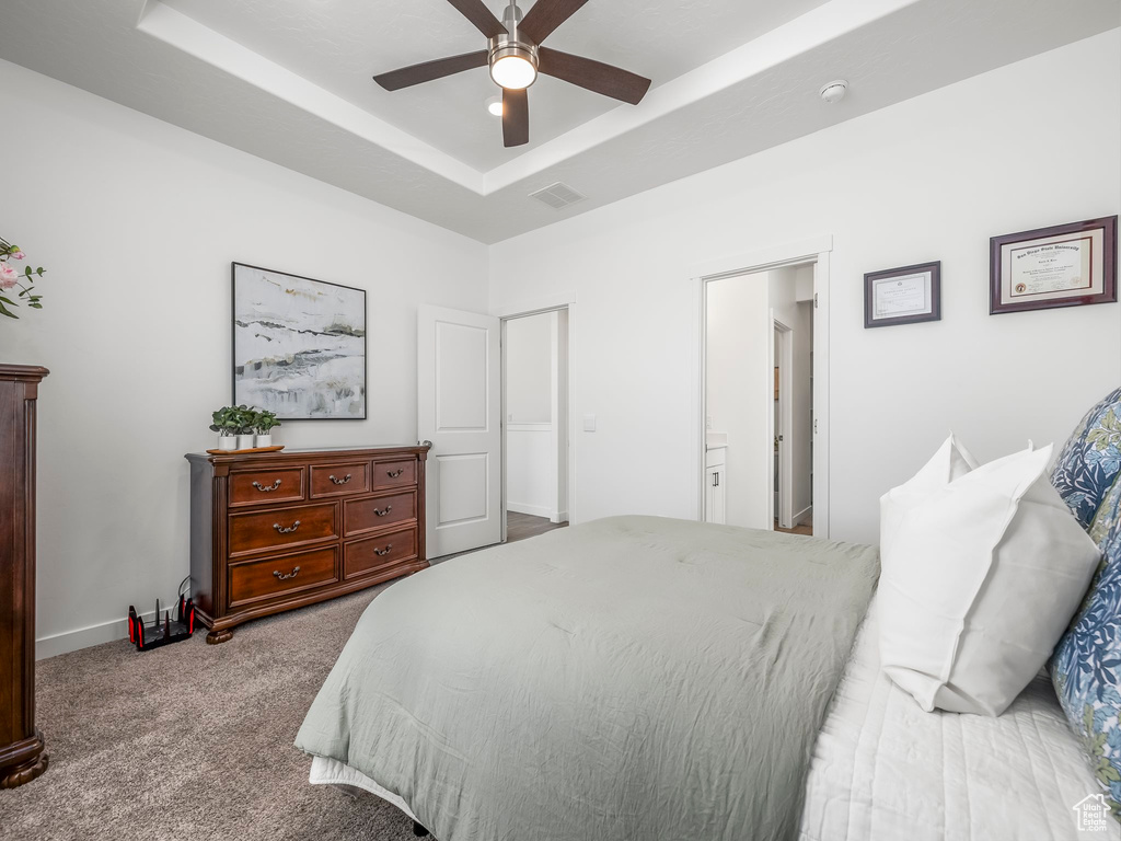 Carpeted bedroom with a tray ceiling, ceiling fan, and baseboards
