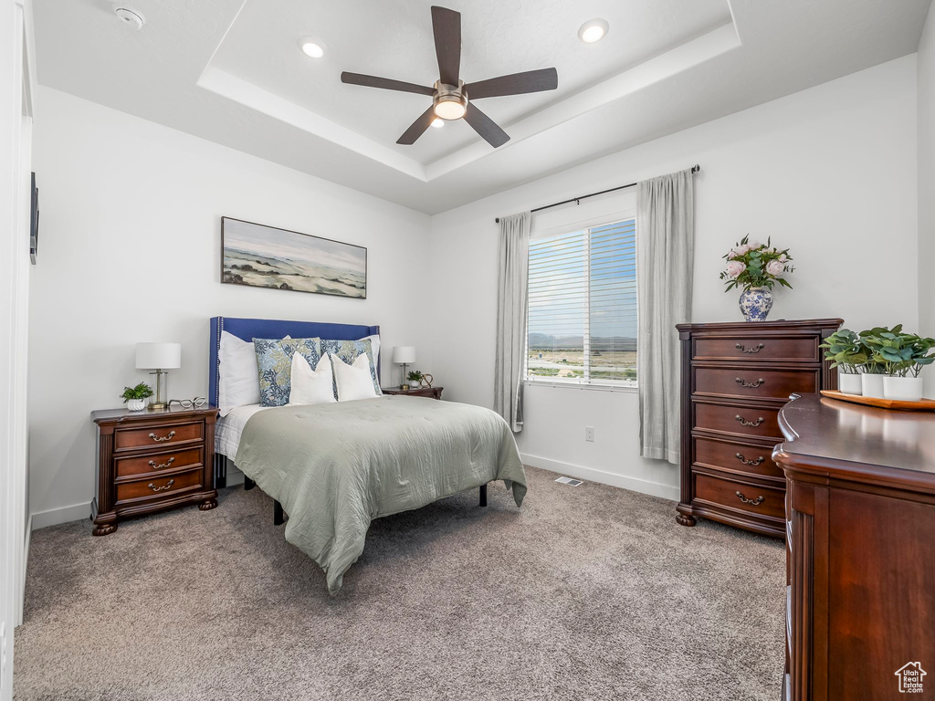 Bedroom with a tray ceiling, light carpet, baseboards, recessed lighting, and a ceiling fan