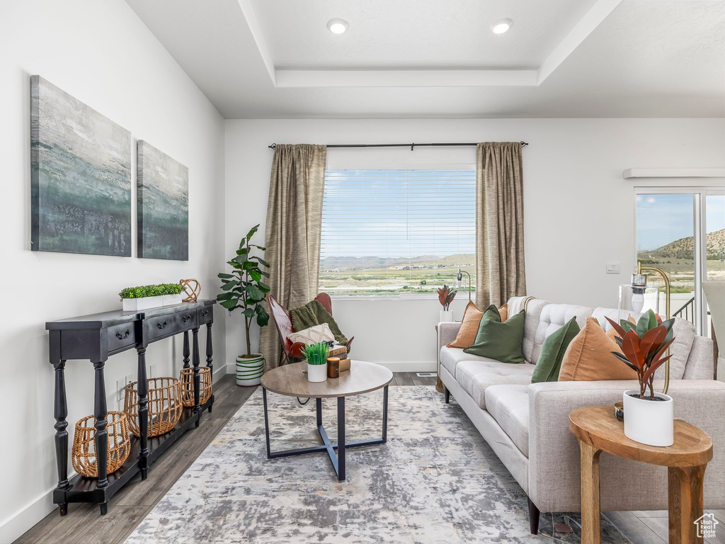 Living room featuring wood finished floors, baseboards, a tray ceiling, and recessed lighting