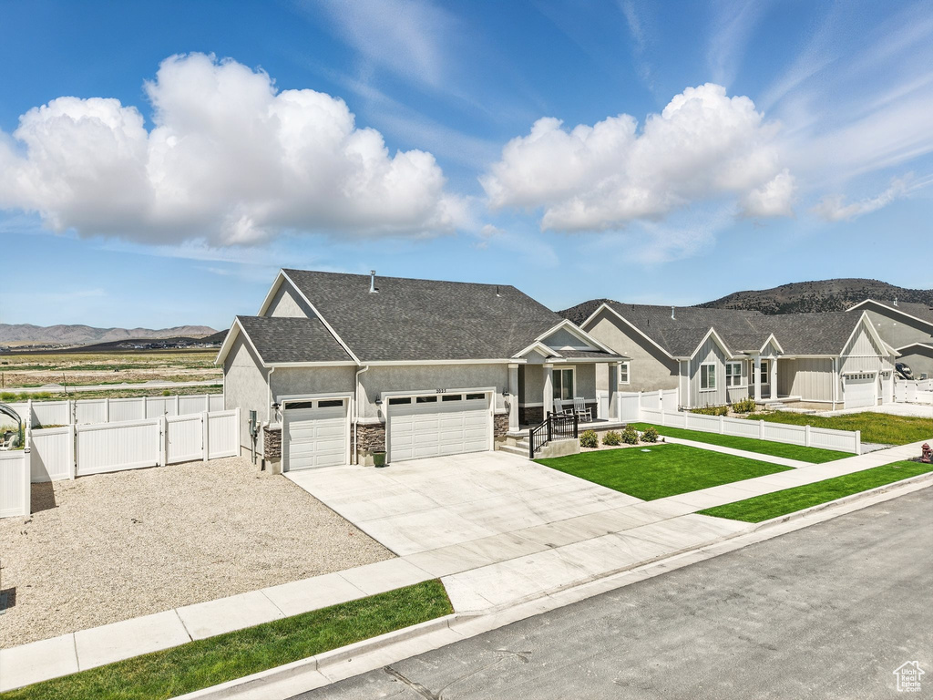 View of front of home with a gate, an attached garage, a mountain view, stucco siding, and concrete driveway