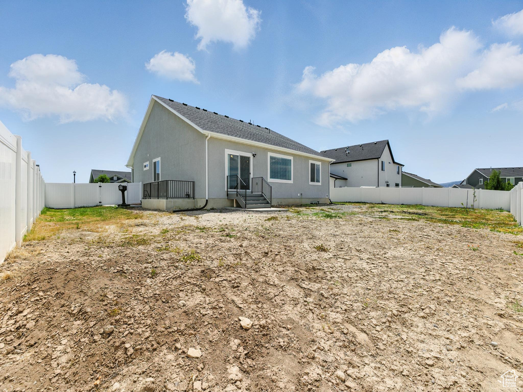 Back of house with a fenced backyard, stucco siding, and a shingled roof