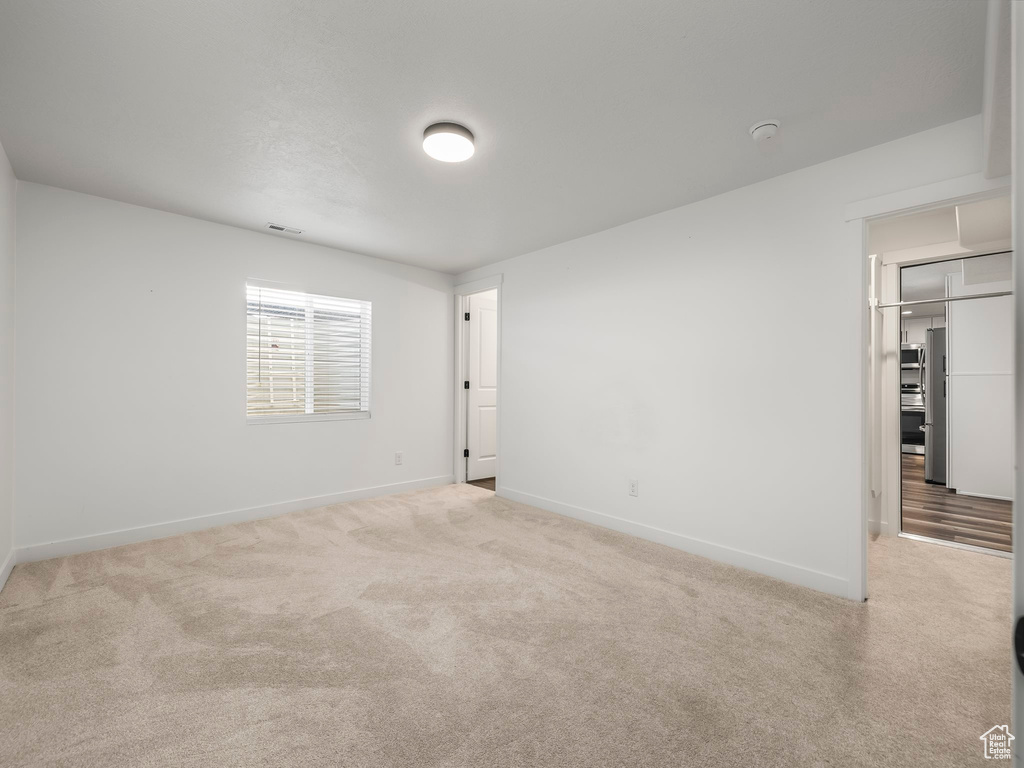 Carpeted spare room featuring baseboards and a smoke detector