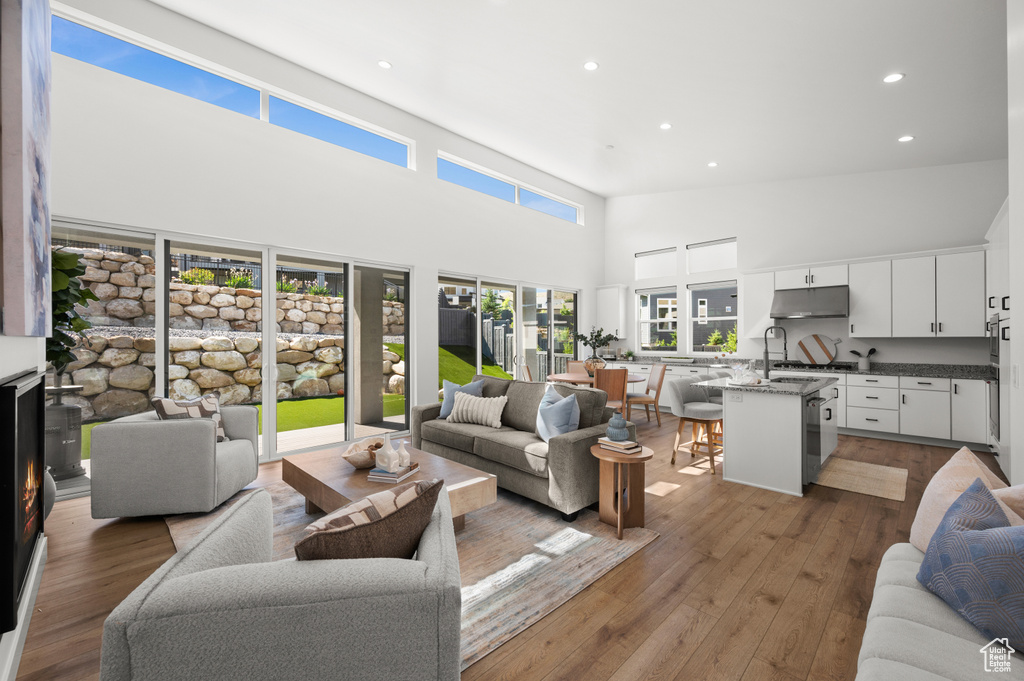 Living area with a towering ceiling, recessed lighting, and light wood finished floors