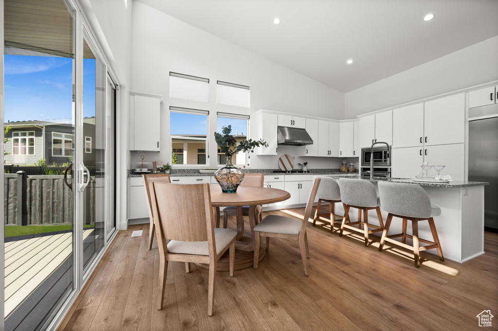 Dining area with high vaulted ceiling, light wood-style flooring, and recessed lighting