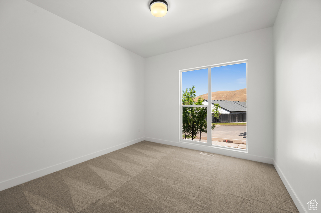 Empty room featuring carpet and baseboards