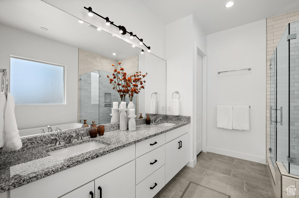 Bathroom featuring double vanity, a shower stall, recessed lighting, a freestanding bath, and baseboards