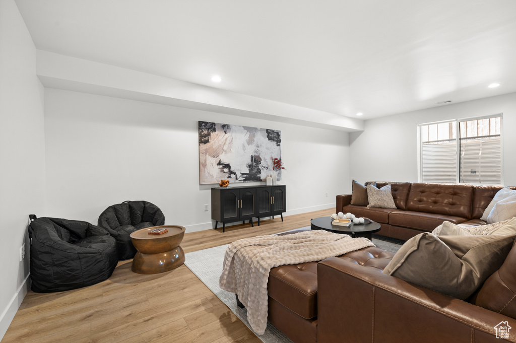 Living room with light wood finished floors, recessed lighting, and baseboards