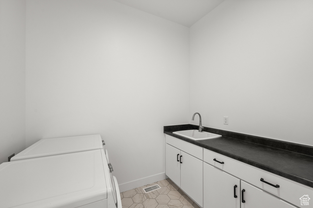 Washroom featuring washer and dryer, cabinet space, and baseboards
