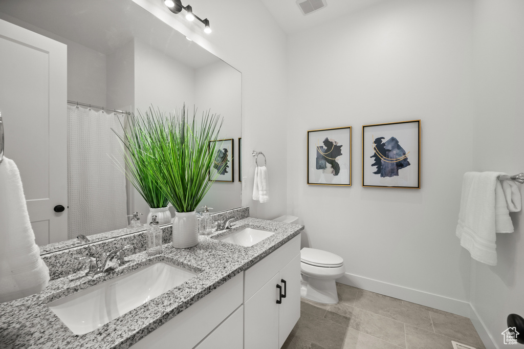 Bathroom featuring double vanity, toilet, and baseboards